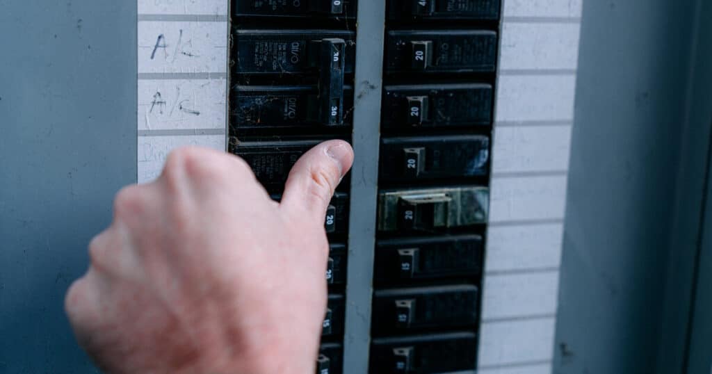 Person is turning off the power to his well pump at the circuit breaker in preparation for these instructions on how to prime a pump for well water.