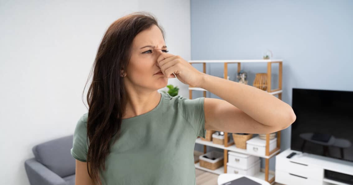 Woman is holding her nose because of a burning smell from furnace.